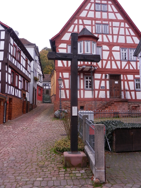 DSCN3782.JPG - Östlich des Marktplatzes befindet sich ein in Deutschland einmaliges schlichtes hölzernes Kreuz mit einer aufrechten Schwurhand und einem nach unten hängenden Schwert. Es ist als Zeichen der Marktgerechtigkeit zu deuten, d.h. daß hier innerhalb eines Burgfriedensbezirks zu bestimmten Tagen Handel getrieben werden konnte. Das Kreuz ist Mitte des 17. Jahrhunderts urkundlich erwähnt und mehrfach erneuert worden. Quelle: Breuberg.de